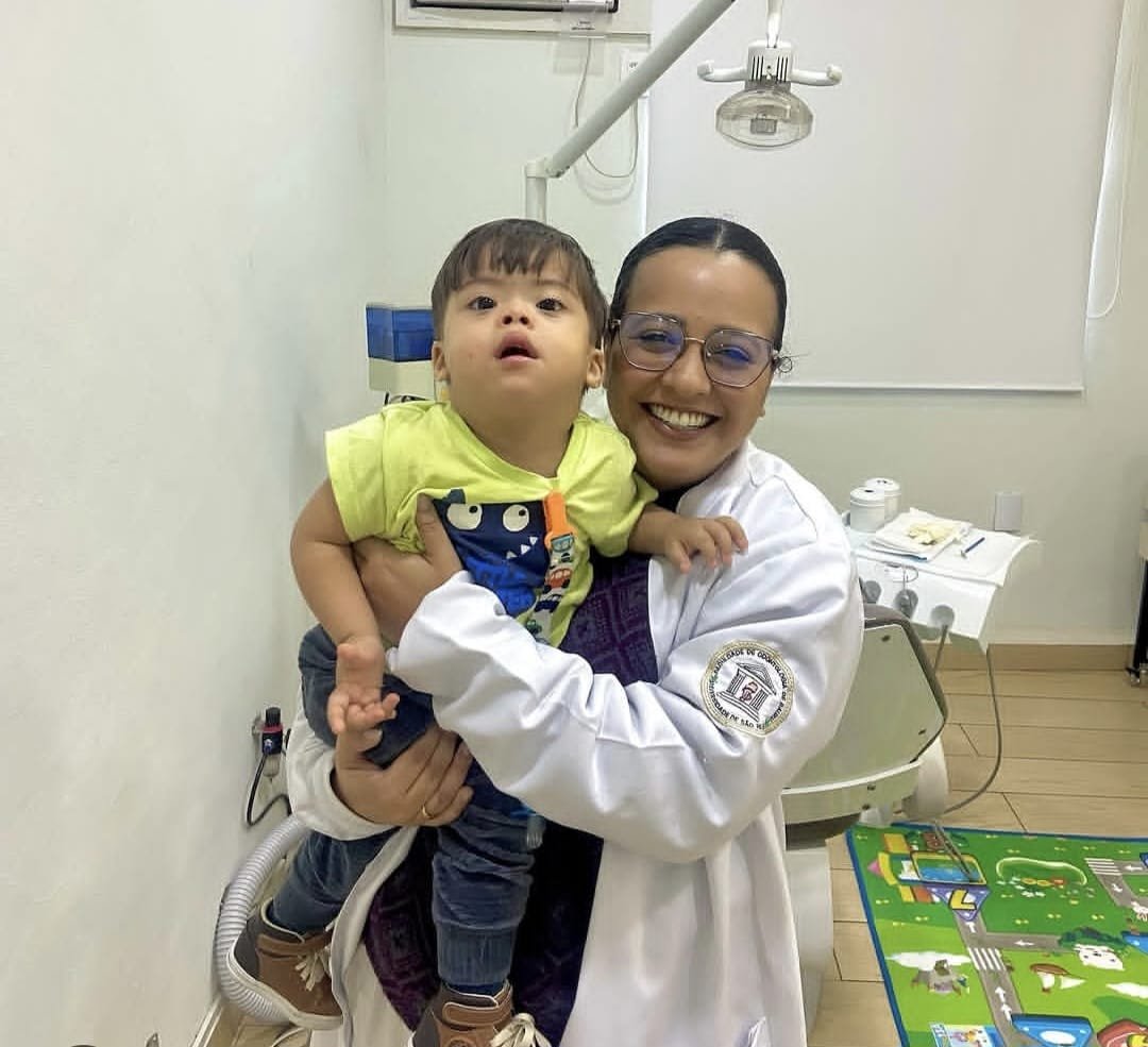 Dra. Marianne Pimentel segurando uma criança no consultório odontológico